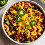 One-Pot Gluten Free Chili Mac served in a white bowl with cheese and jalapeños