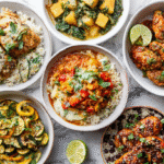 Food collage featuring ten chicken dishes, including coconut lime chicken, creamy Tuscan chicken, sheet pan lemon garlic chicken, chicken chili, quinoa veggie chicken bowl, crispy chicken cutlets, honey garlic chicken thighs, stuffed zucchini boats, chicken taco bowl, and a chicken sweet potato skillet, arranged on a bright white kitchen table.