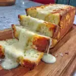 Loaf of freshly baked 2-ingredient cottage cheese bread on a wooden cutting board.