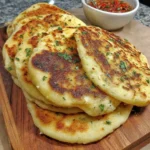 Fluffy gluten free naan bread on a wooden board with herbs and spices.