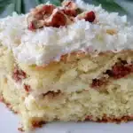 Delicious gluten free Italian Cream Cake topped with cream cheese frosting and nuts