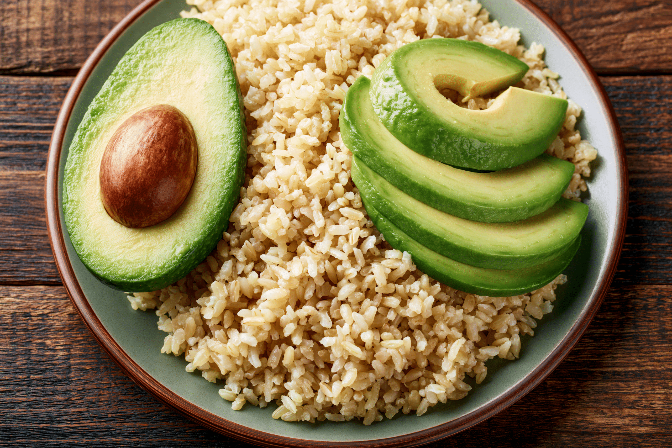 A balanced plate featuring complex carbohydrates like brown rice and healthy fats such as avocado slices, alongside a lean protein source, illustrating a meal optimized for energy and essential functions.