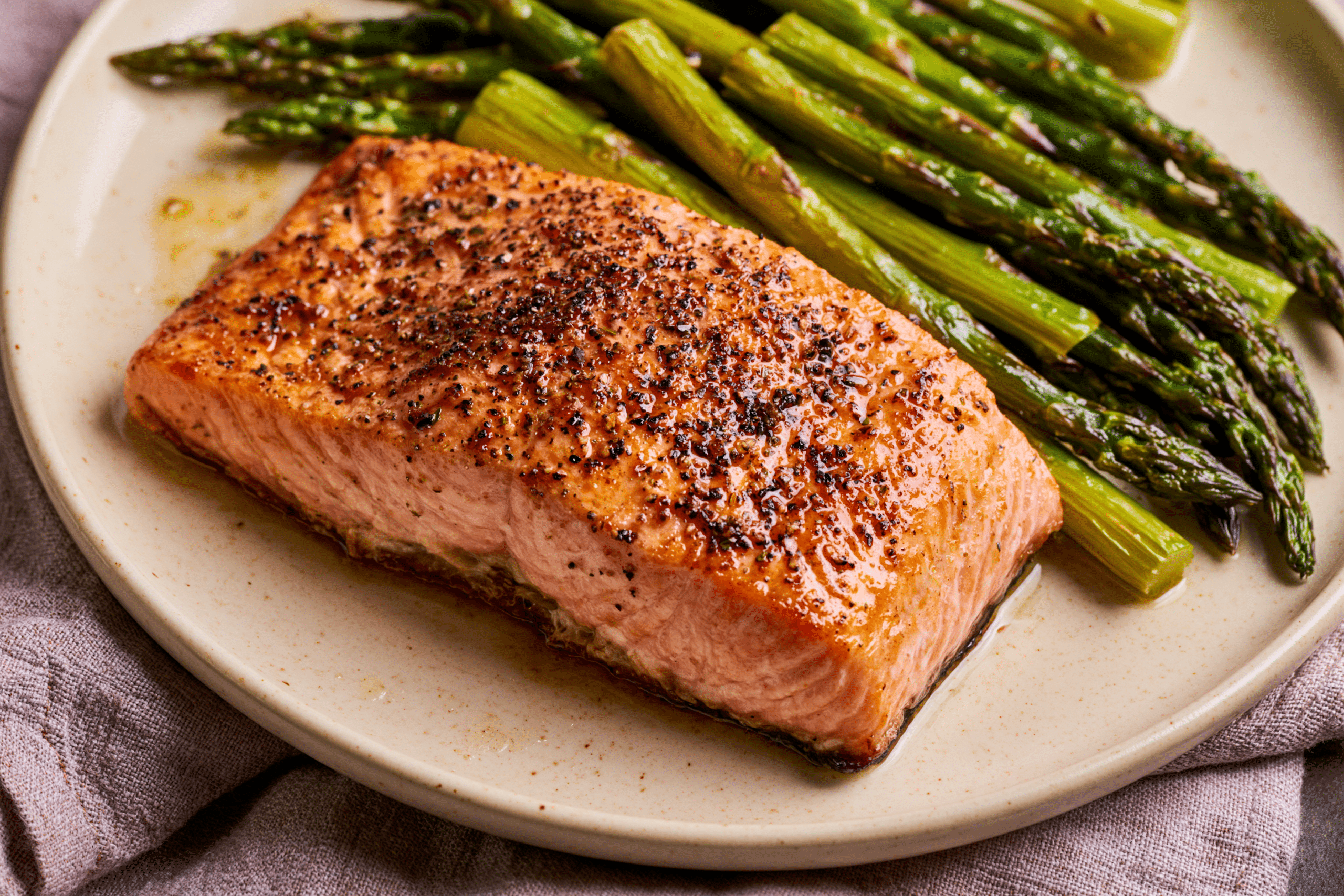 A perfectly cooked salmon fillet with roasted asparagus spears on a plate, ready for a high-value dinner.