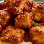 Plate of baked Gochujang tofu garnished with spices and vegetables