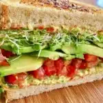 Veggie hummus avocado sandwich with fresh vegetables and whole grain bread