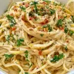 Creamy vegan lemon pasta dish garnished with herbs and lemon zest.