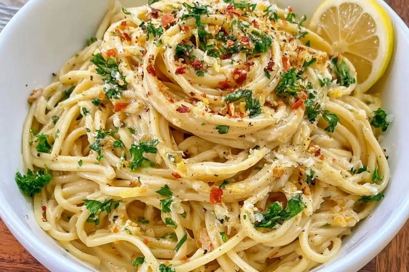 Creamy vegan lemon pasta dish garnished with herbs and lemon zest.