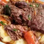 Slow Cooker Garlic Herb Pot Roast with vegetables and herbs in a serving dish.