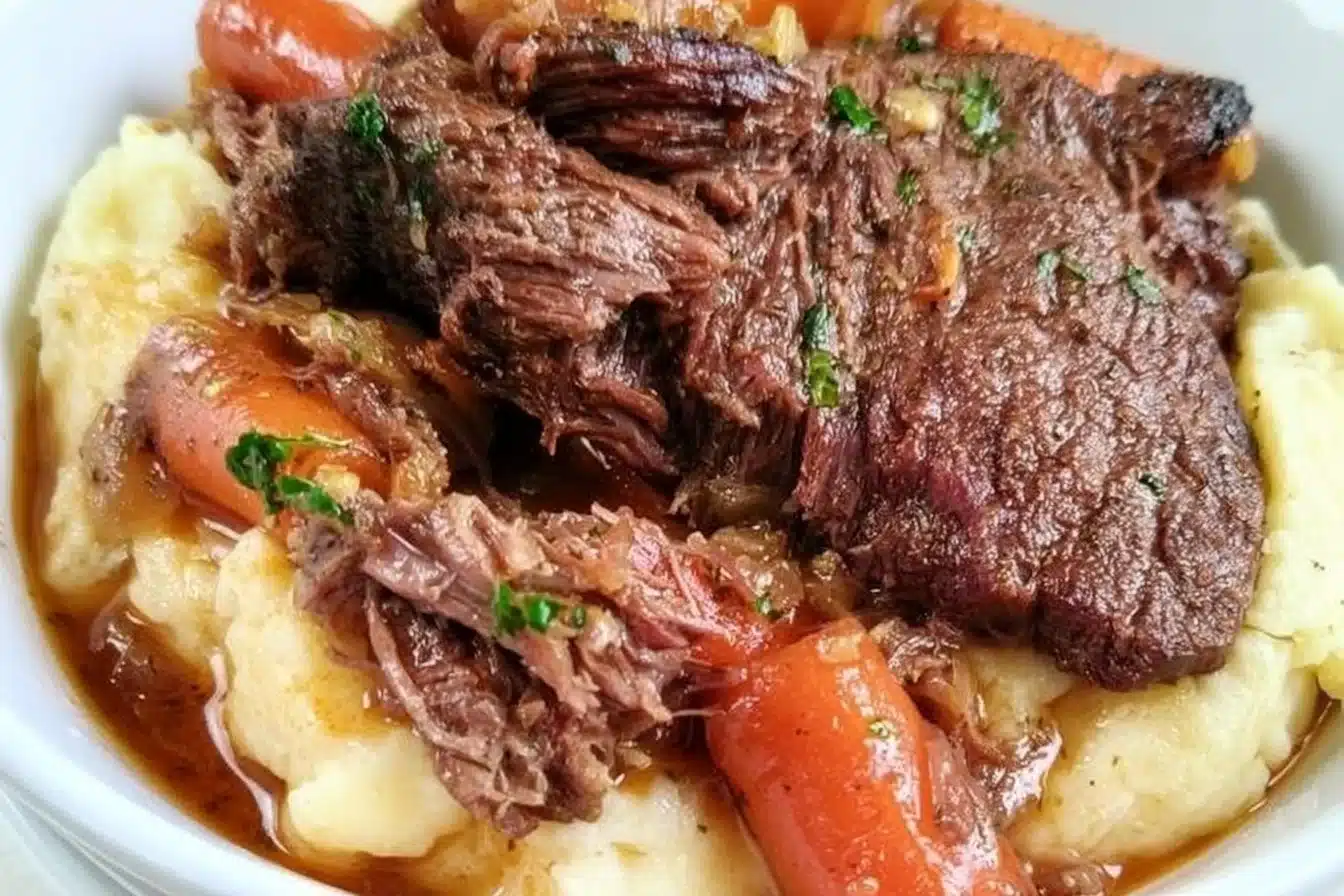 Slow Cooker Garlic Herb Pot Roast with vegetables and herbs in a serving dish.