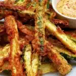 Crispy keto zucchini fries served with dipping sauce on a plate