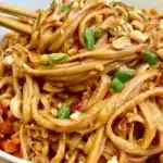 Delicious spicy peanut butter noodles garnished with fresh vegetables.