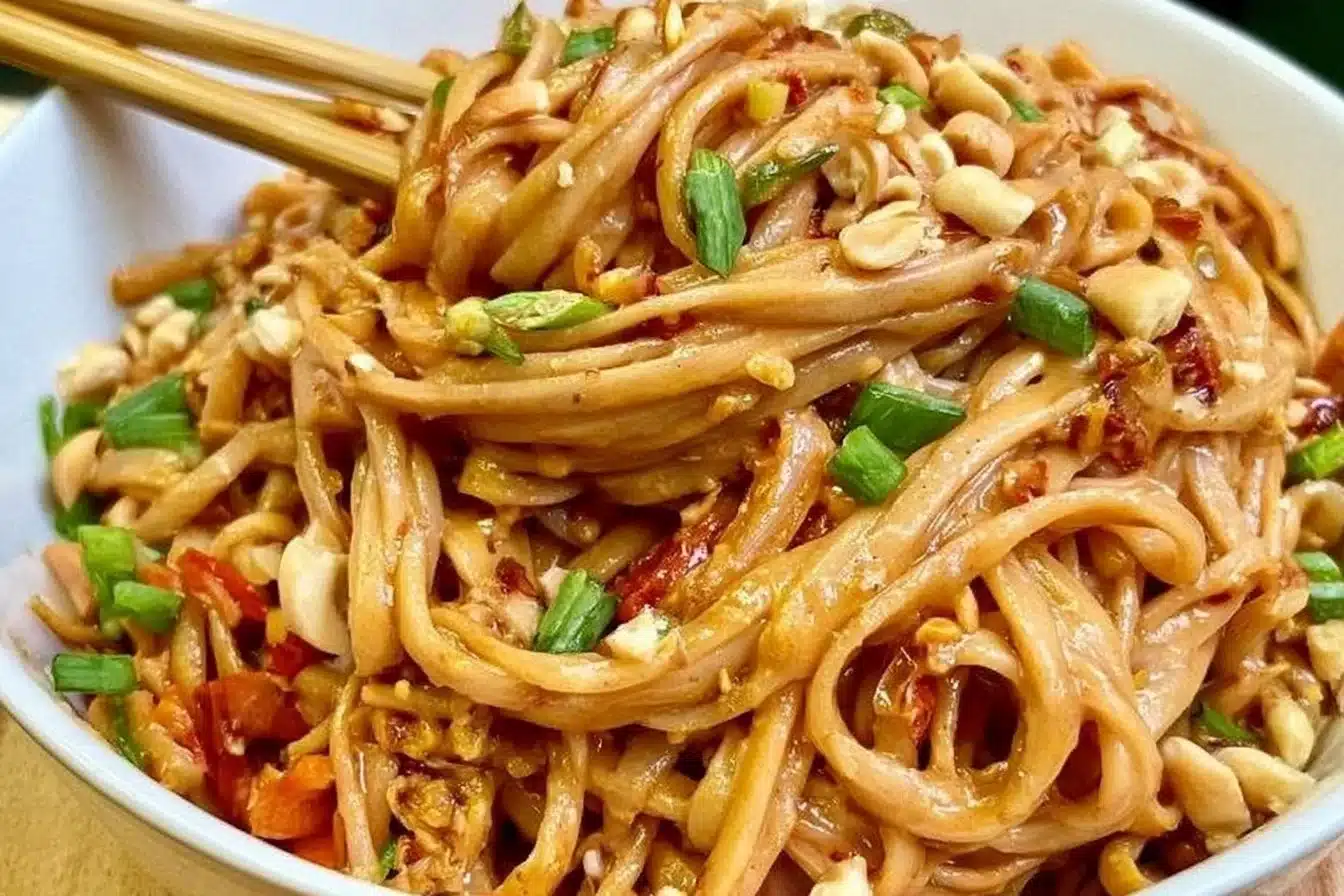 Delicious spicy peanut butter noodles garnished with fresh vegetables.