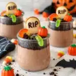 Glutenfreie Graveyard Dirt Cups decorated with edible tombstones and worms.